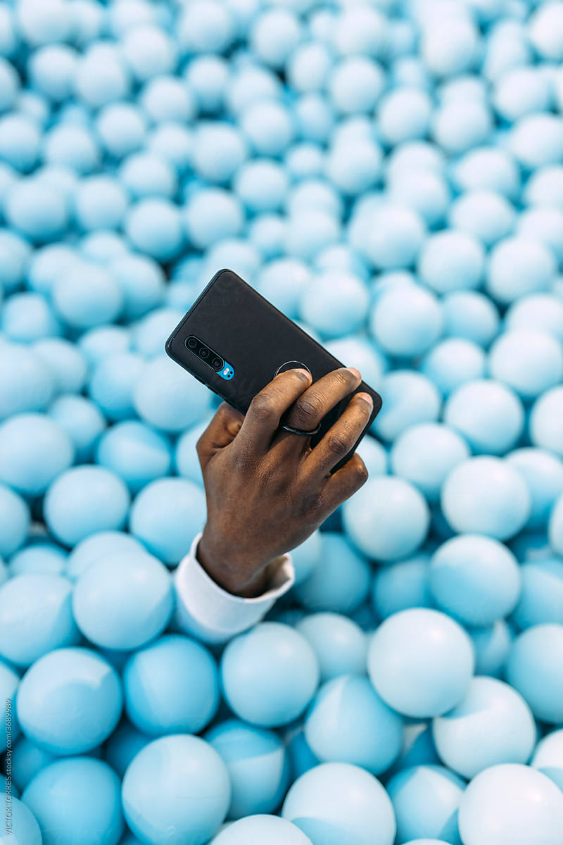 Crop black man with smartphone in ball pit