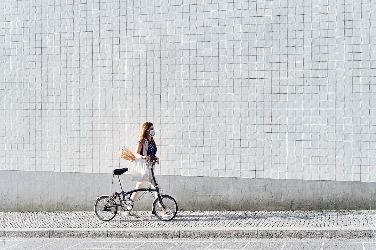Woman in a face mask walking with a bike