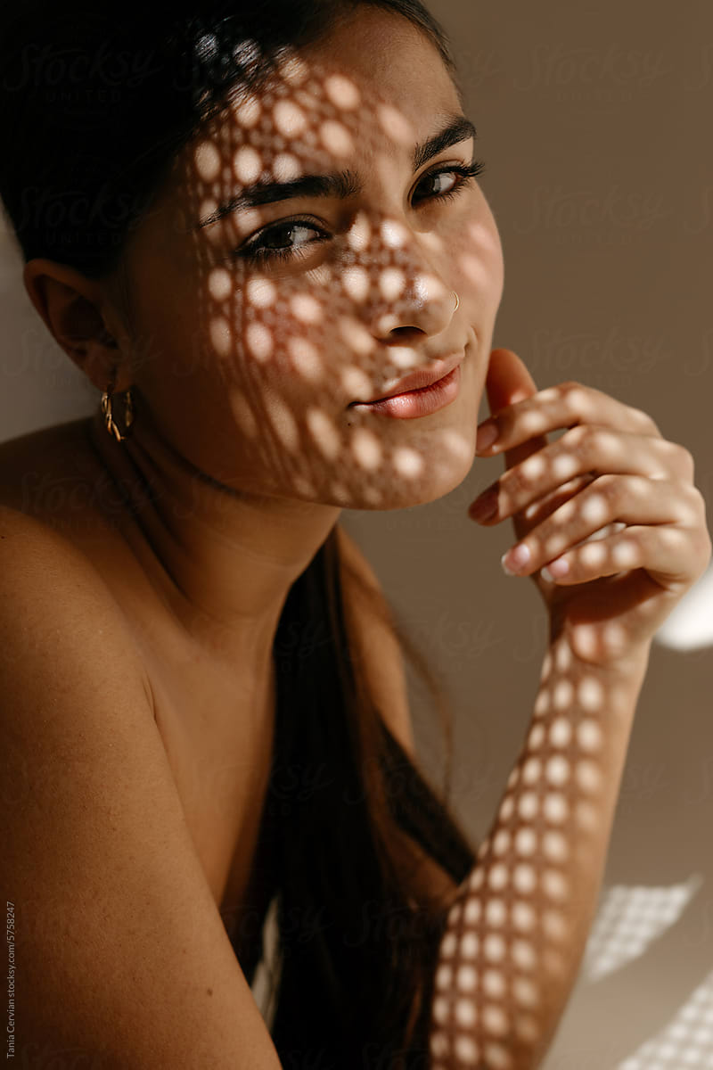 Sensual woman with makeup under perforated light shadow