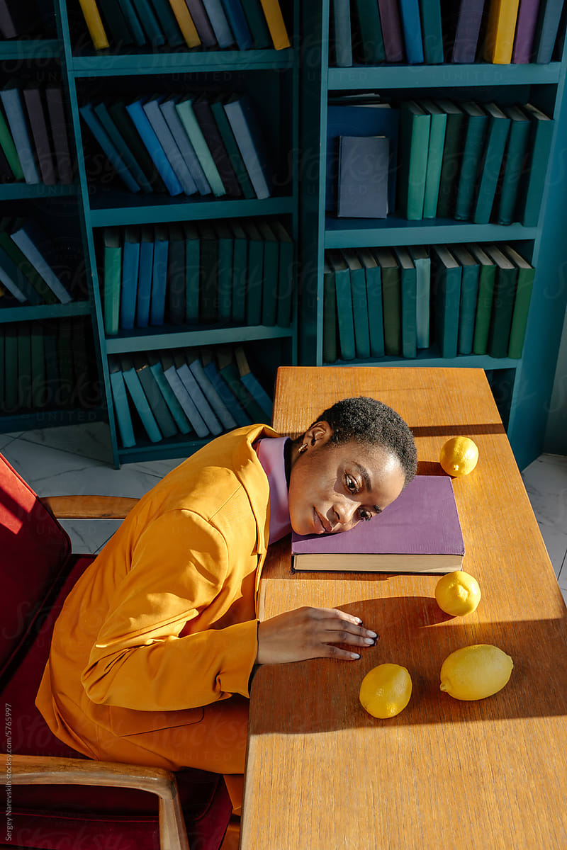 Woman with head on book, lemons on table