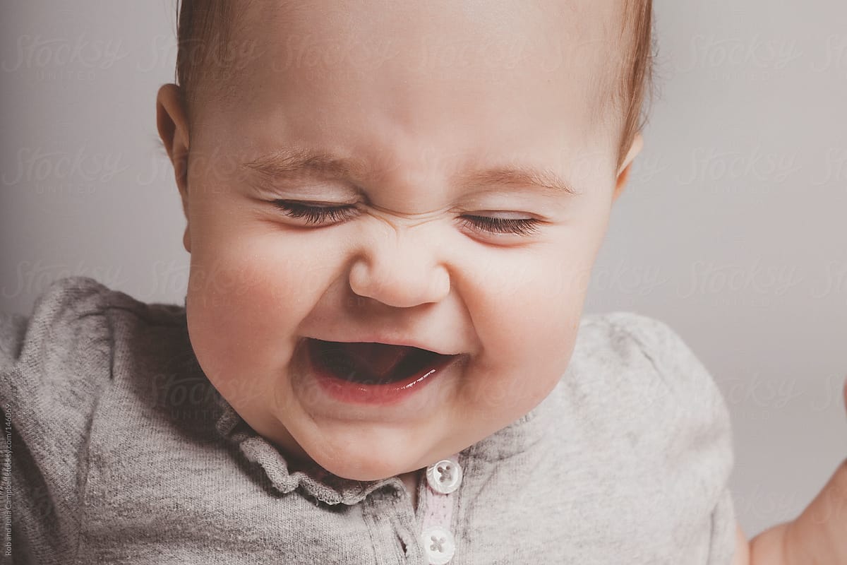 Cute baby girl laughing on solid background