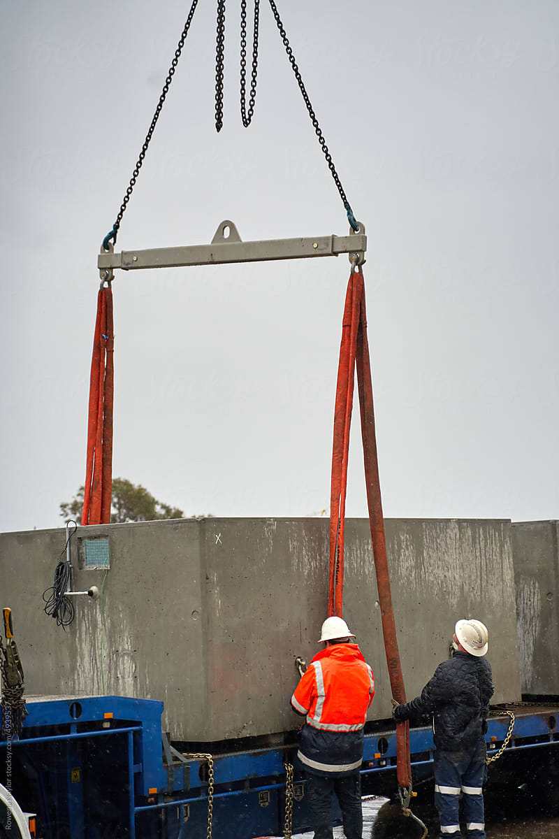 Workmen attaching crane straps to load