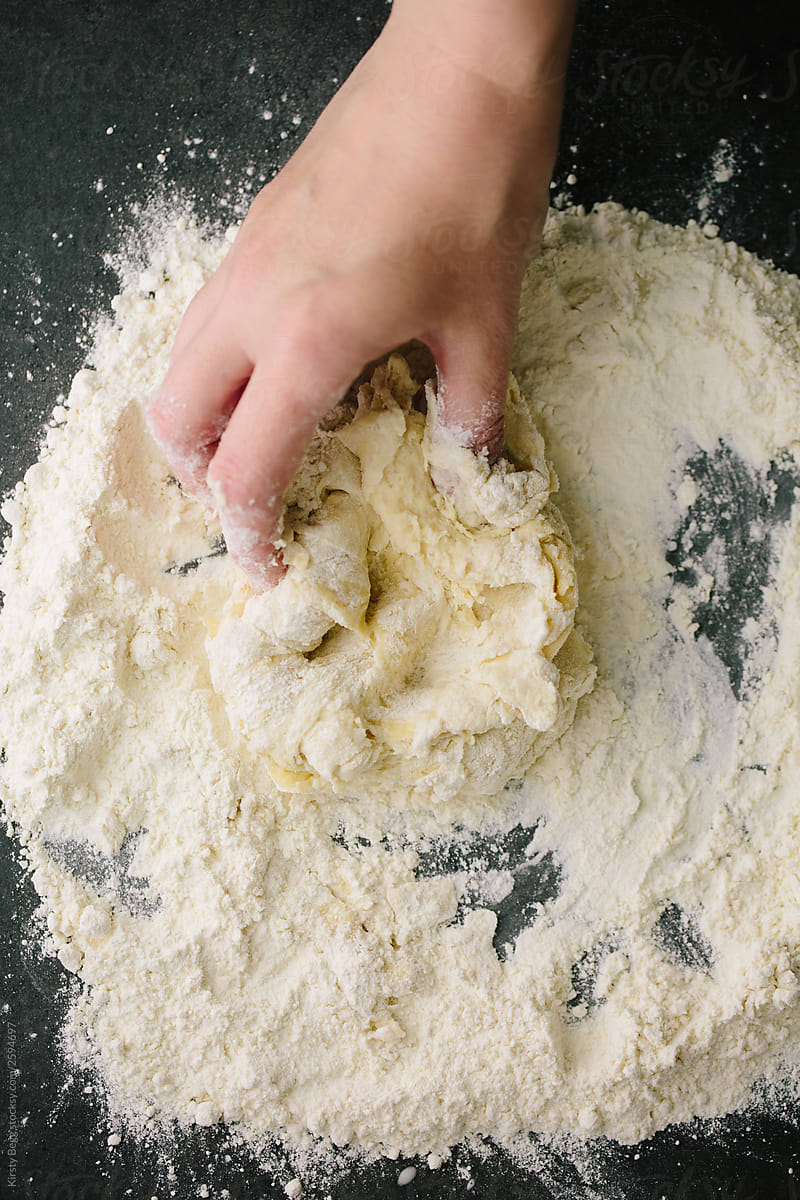 Woman bringing dough together in flour