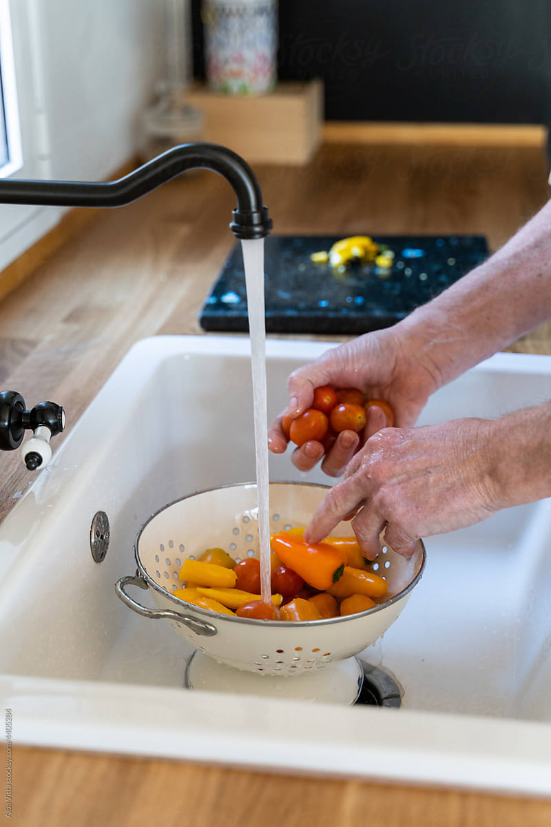 Senior man washing vegetables at kitchen sink