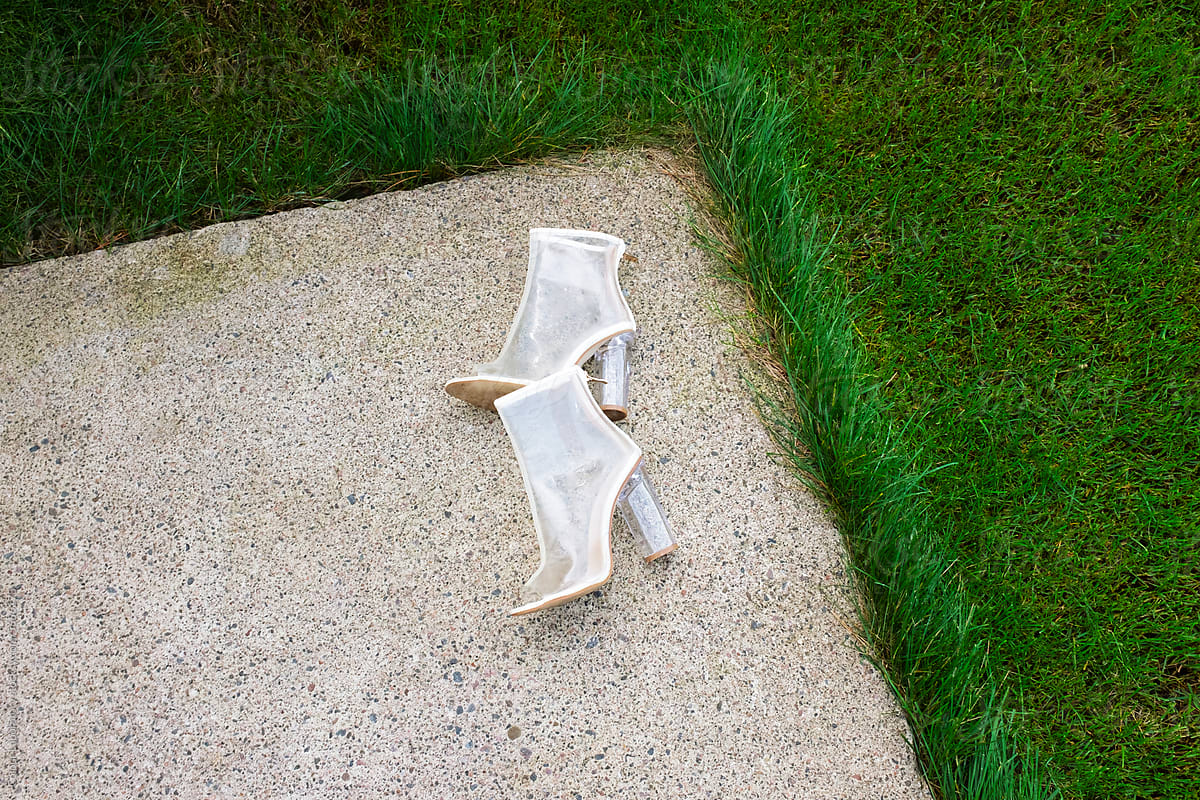 Transparent plastic classic heels laying on a  green grass in a garden