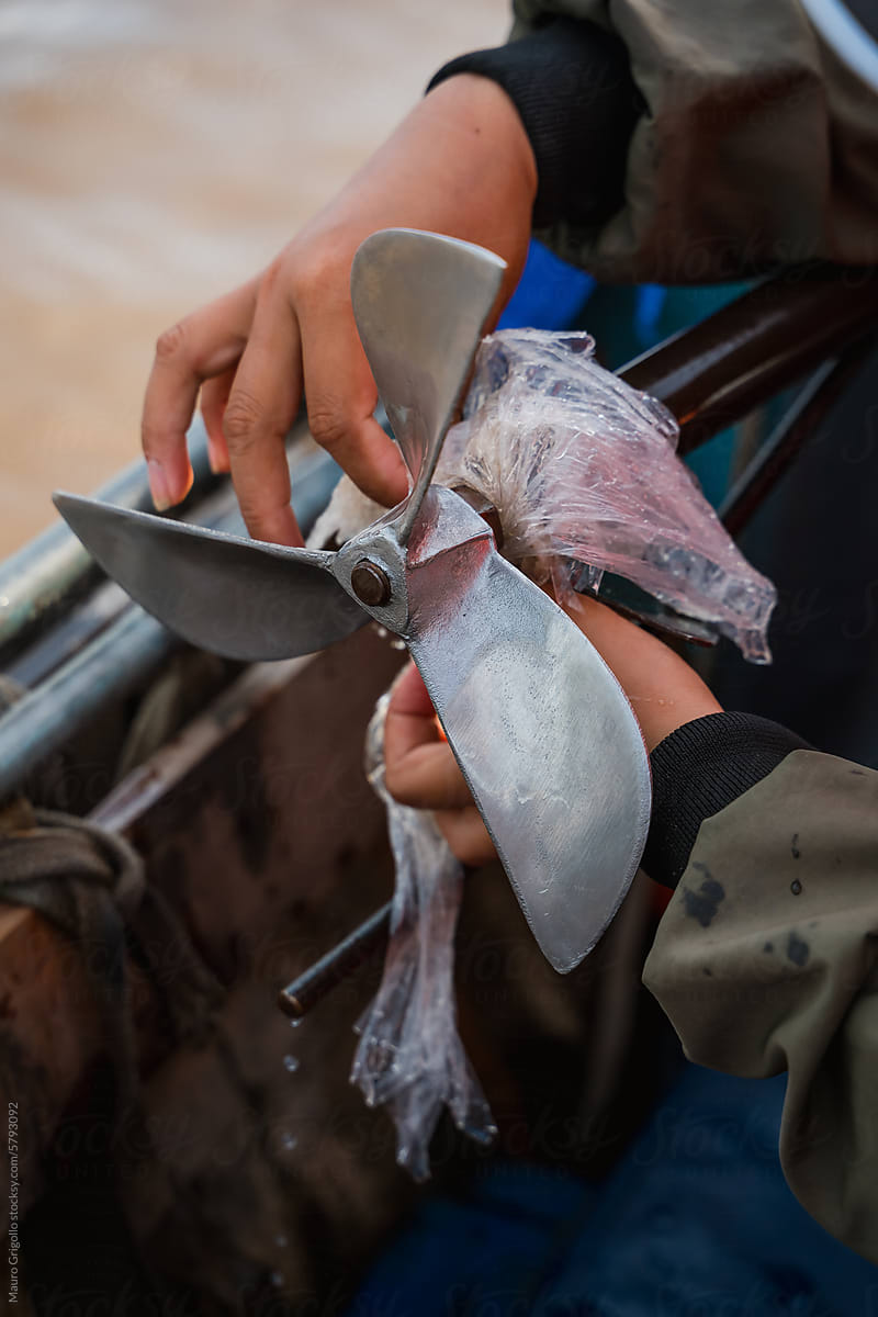 A person removing plastic from a boat propeller