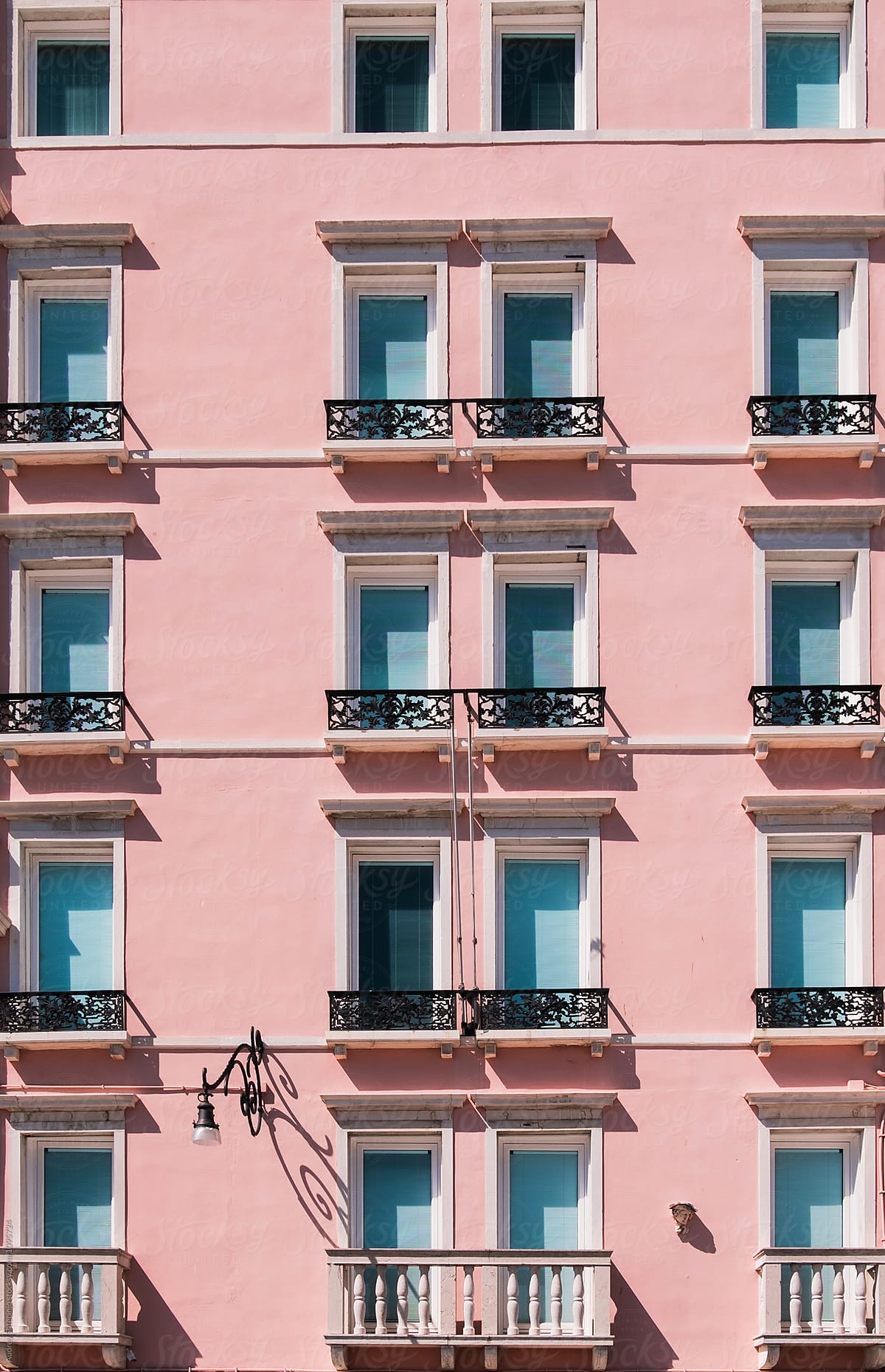 Pink building facade with blue/cyan windows.Italy