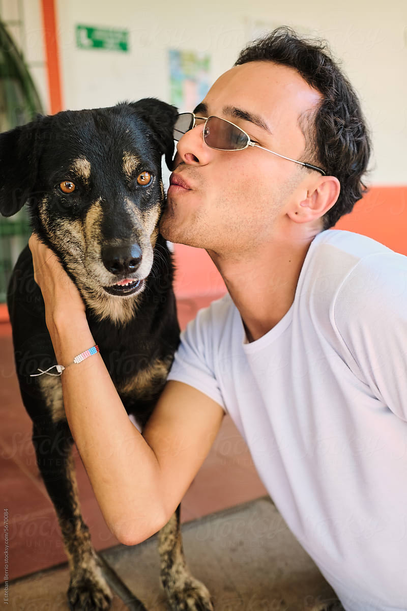 Latino man kissing a dog