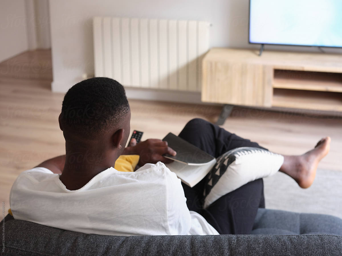 Black male with book and TV remote