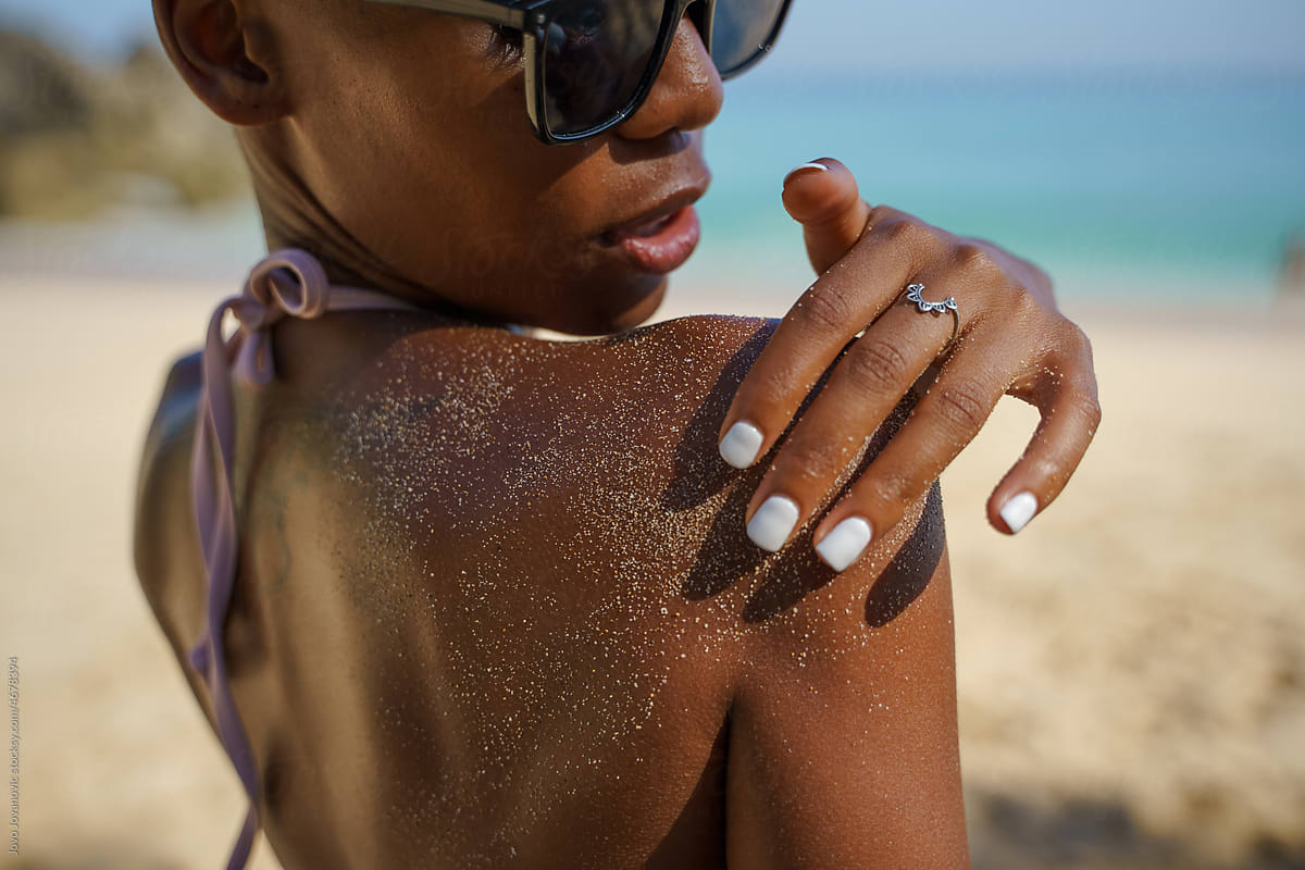 Close up of black woman\'s hand brushing sand off shoulder