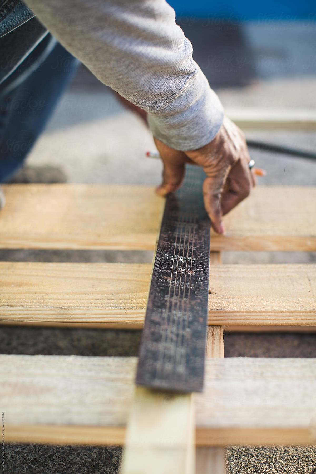 A man measuring a wooden pallet using a t square ruler