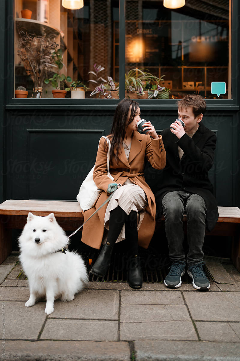 A couple with a dog is drinking a coffee out of a cafeteria