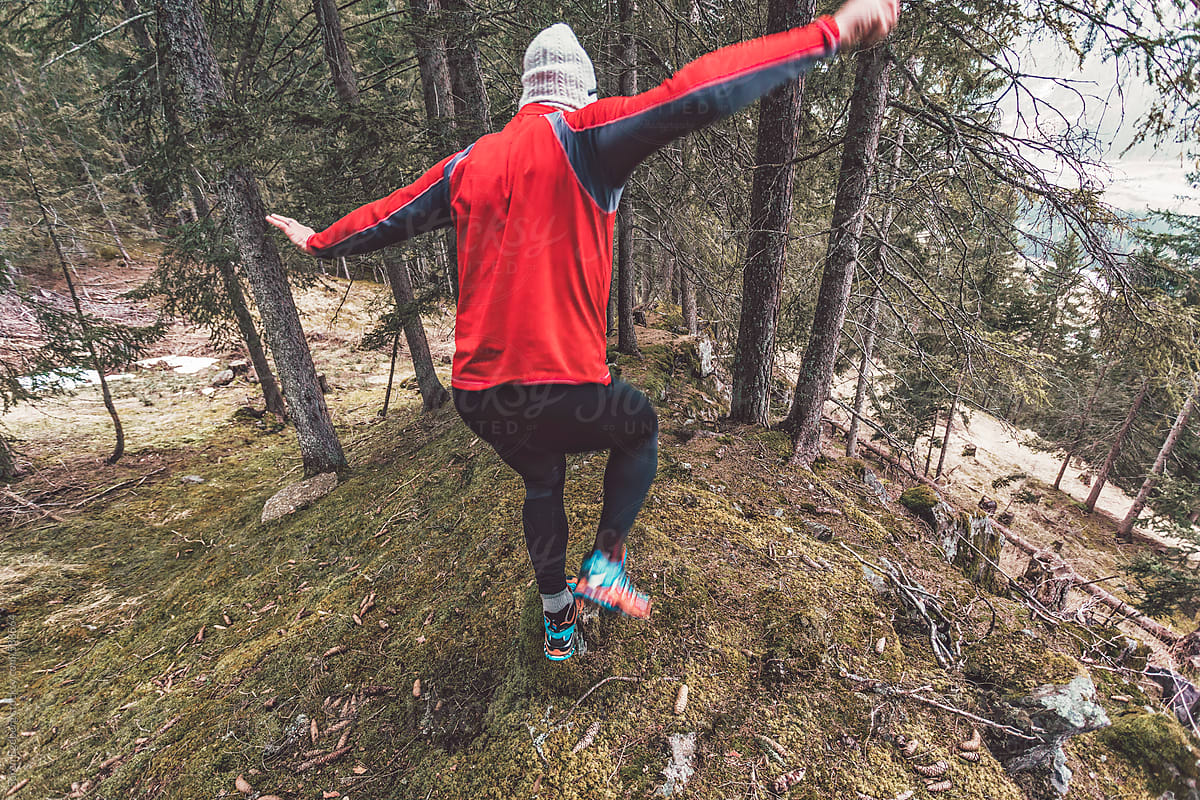 Runner jumping down forest mountains trail in spring