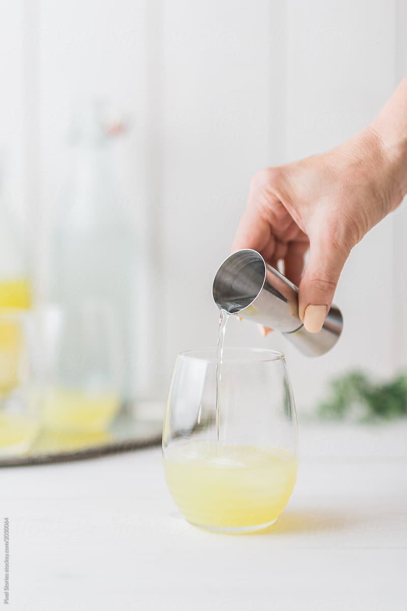Woman adding gin to fizz alcohol cocktail with Limoncello
