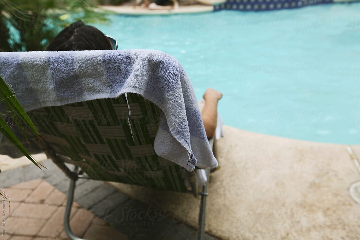 Woman reclines in retro lounge chair by pool