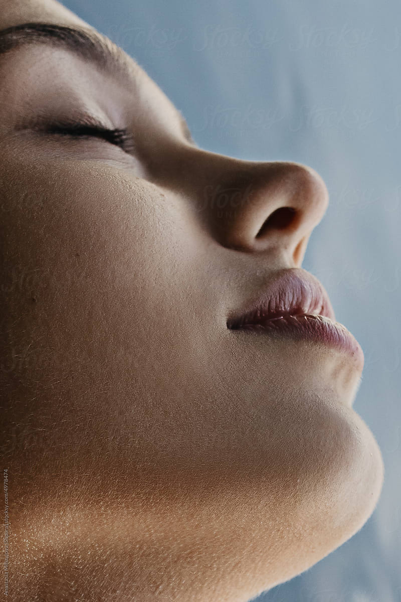 Half-face profile portrait of tanned female with closed eyes in water