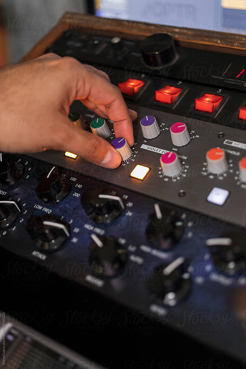 Left hand moving red buttons on a black audio console