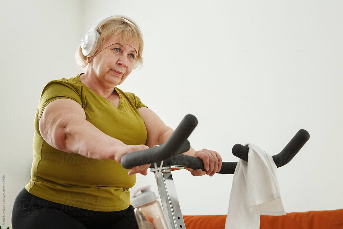 Mature woman exercising on cycling machine at home