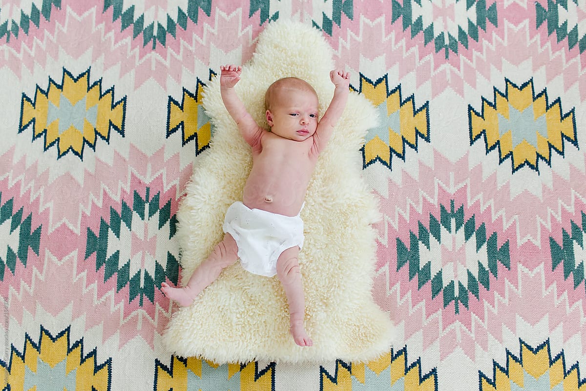 View Newborn Laying On A Sheepskin And A Patterned Rug By Stocksy