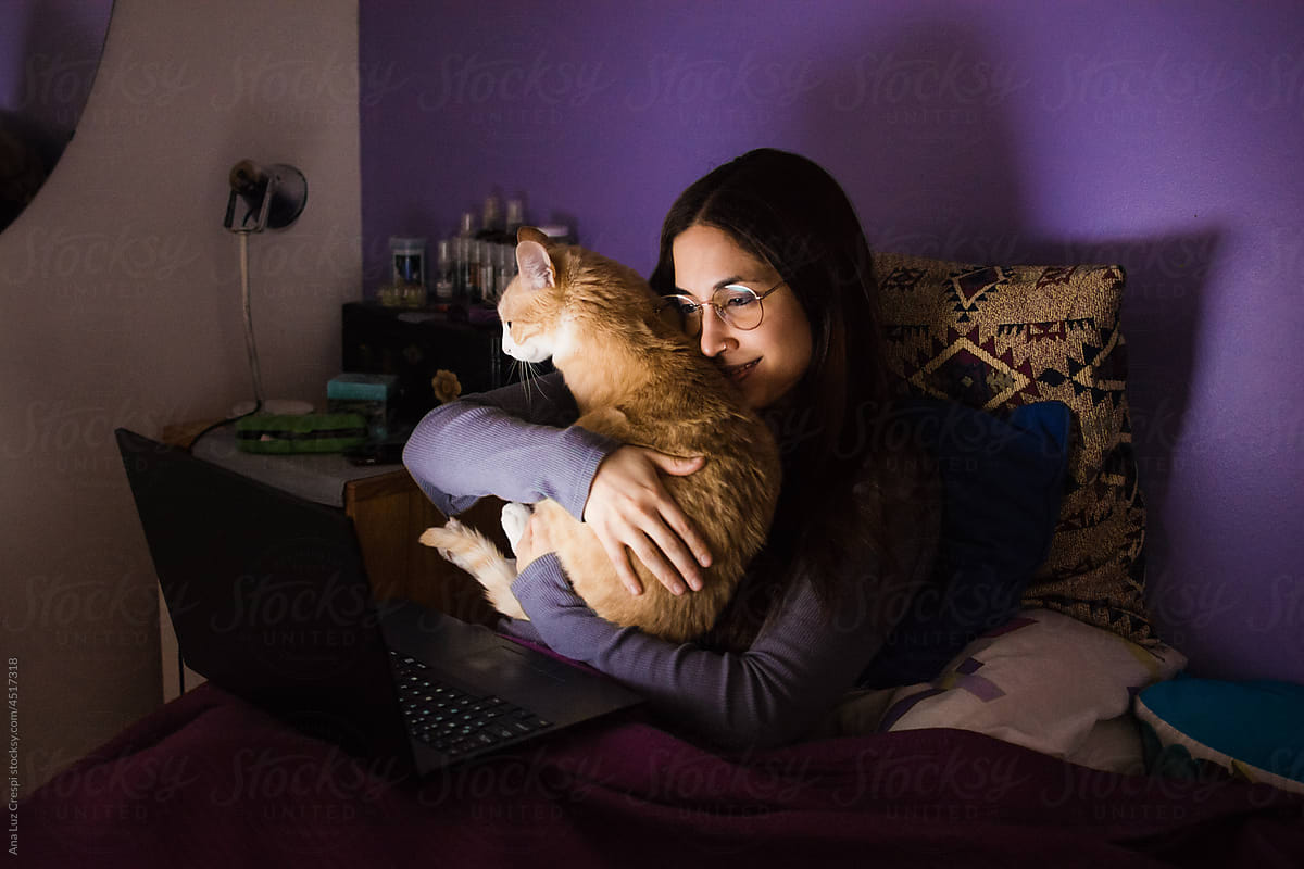 Woman hugging her cat while watching a movie online