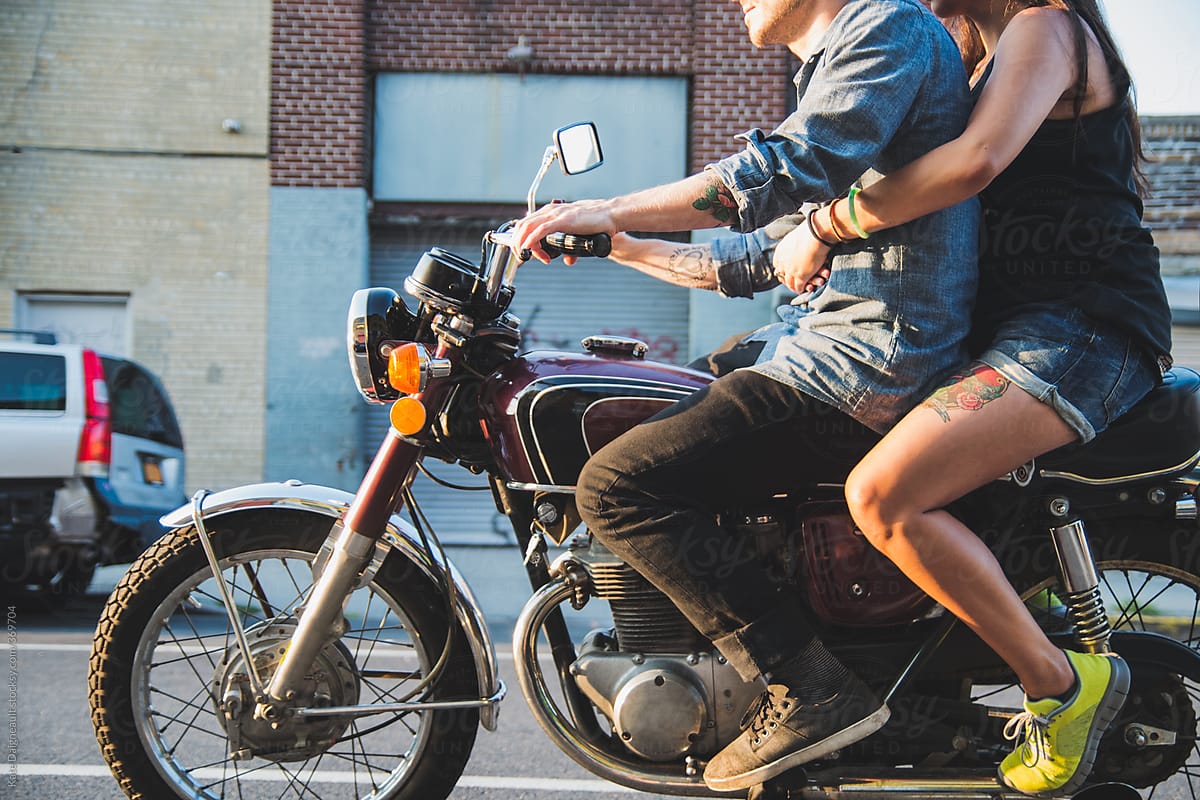 Side view of man and woman riding motorcycle in city