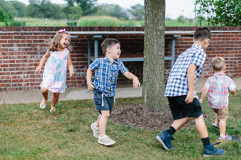 Group of children chasing a toddler playfully