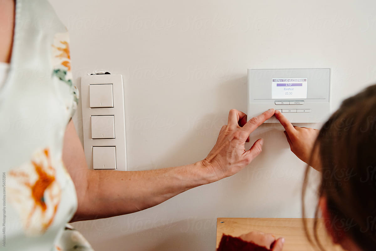 Mother and daughter using smart thermostat at home