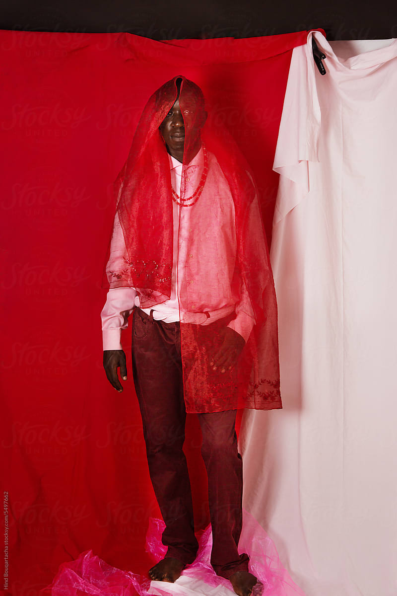 Young black man wearing pink posing at the studio with a red scarf