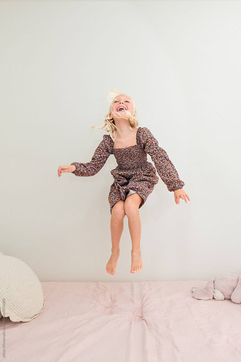 Carefree girl jumping on her bed