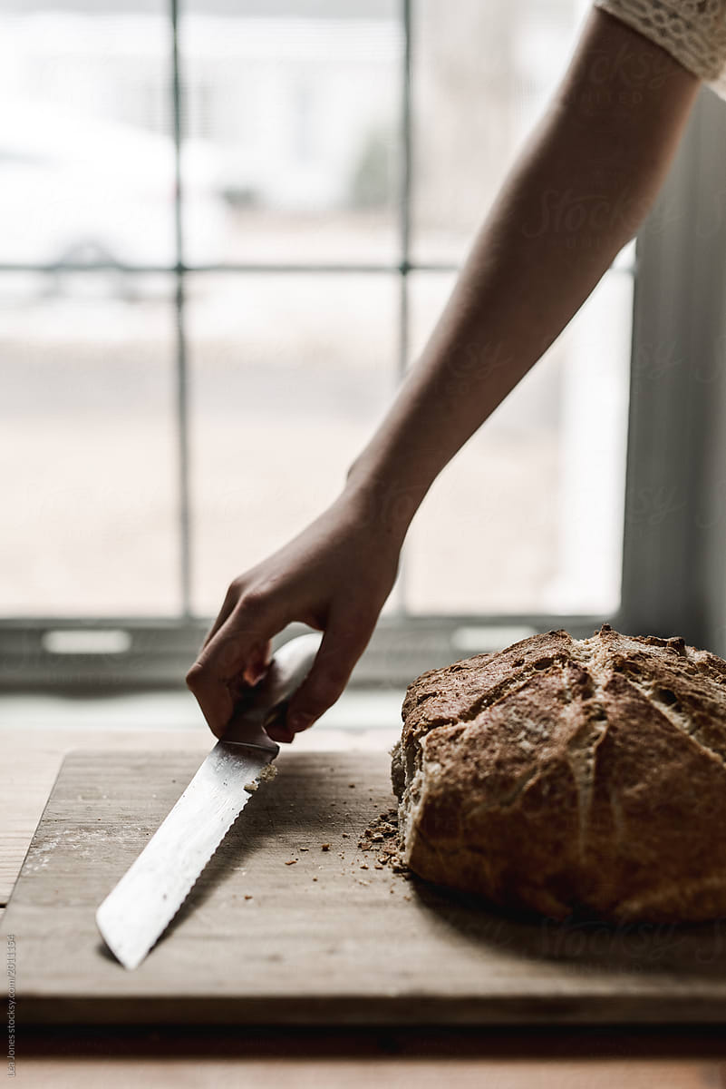 fresh baked bread with hand reaching for knife
