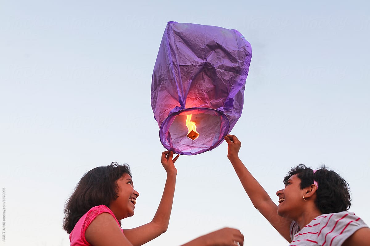 Girls releasing chinese sky lantern to the sky at twilight