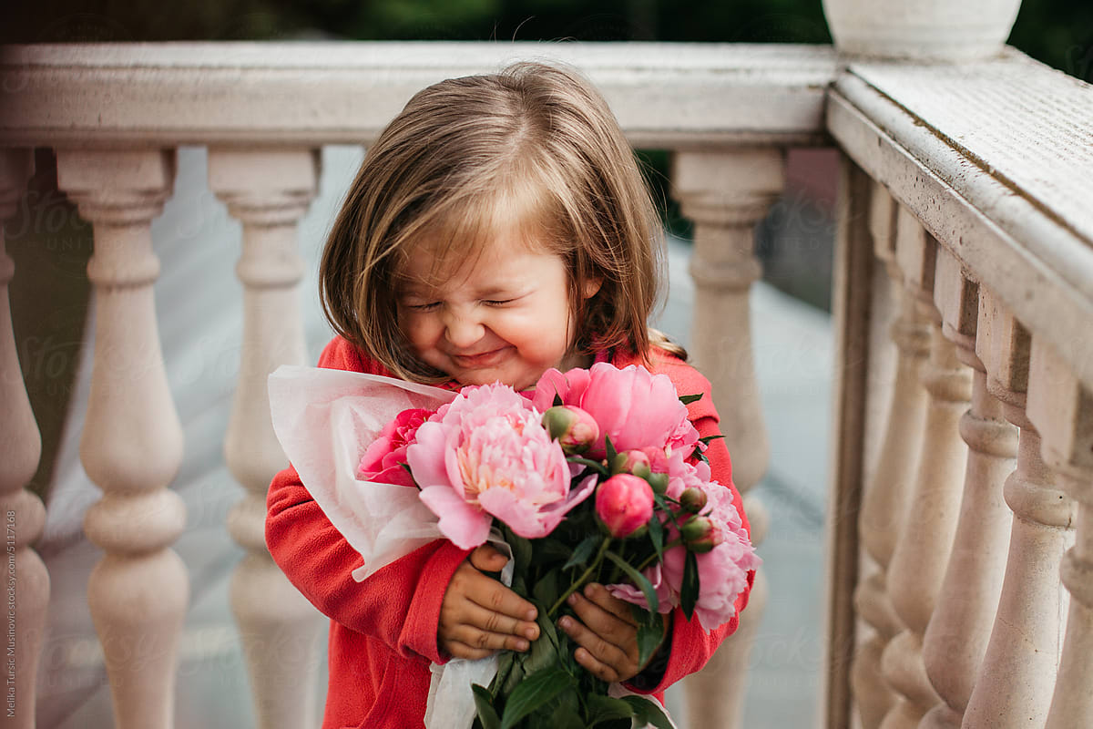 Little girl holding bouquet of peonies