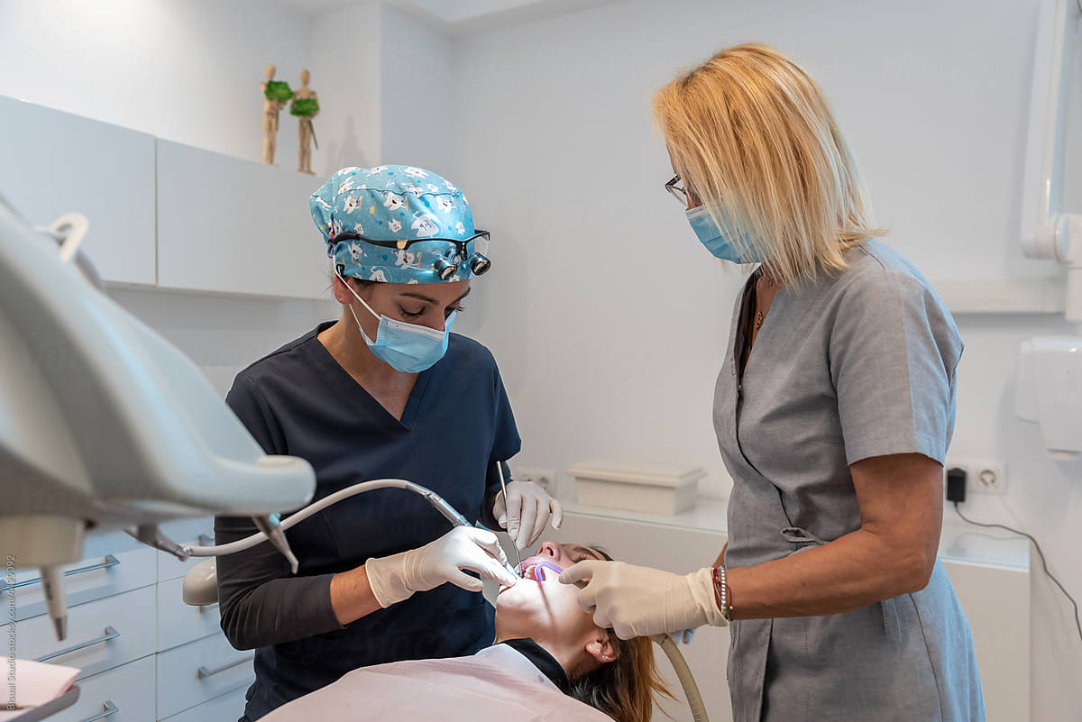 Orthodontist making a dental cleaning to patient with an assistant