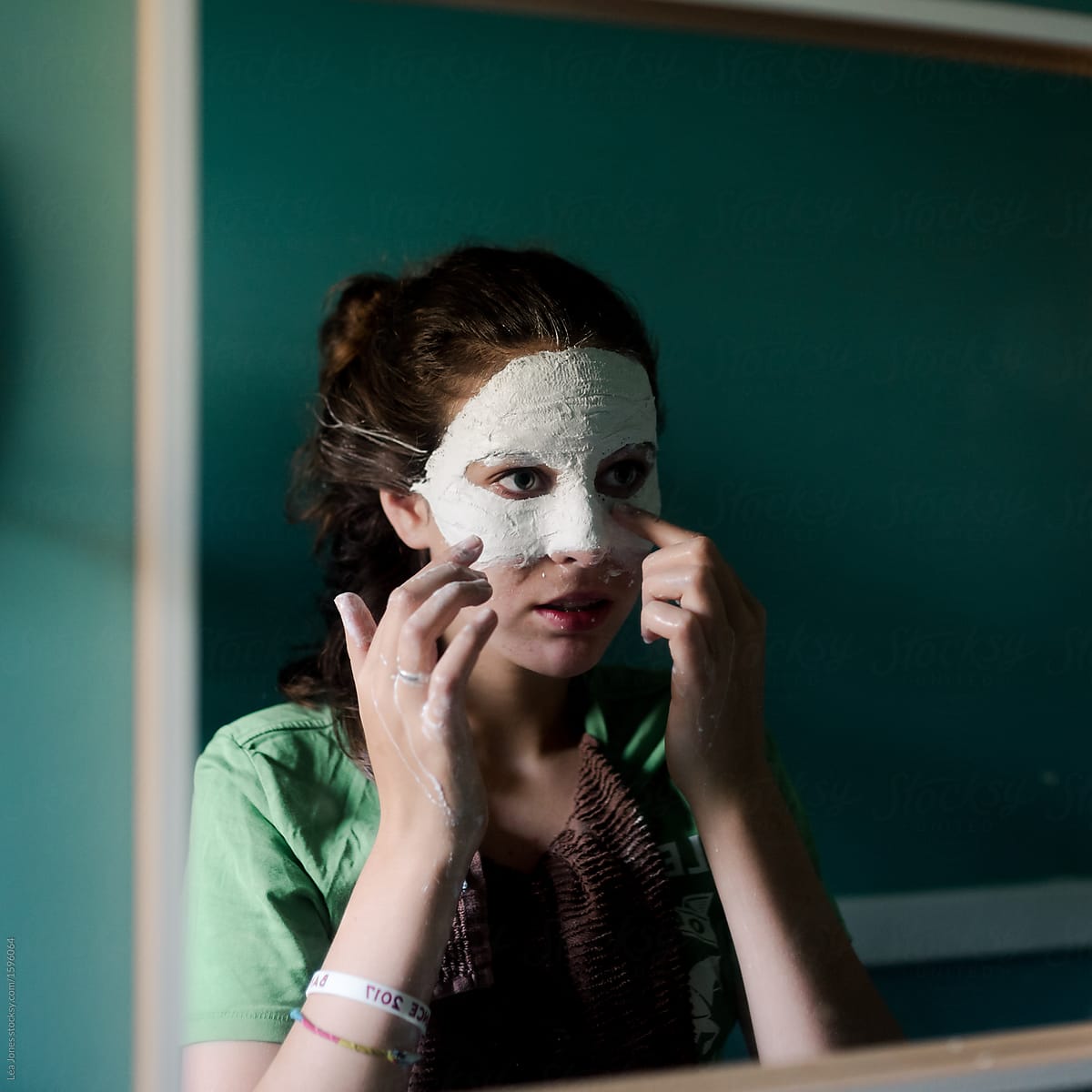 teen girl creating a mask/masquerade (in mirror)