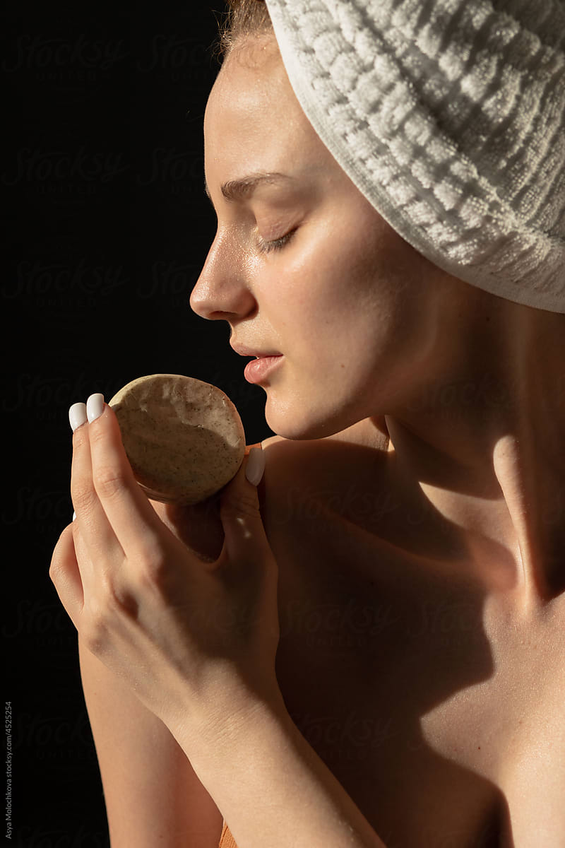 Young beautiful model posing with organic soap in studio