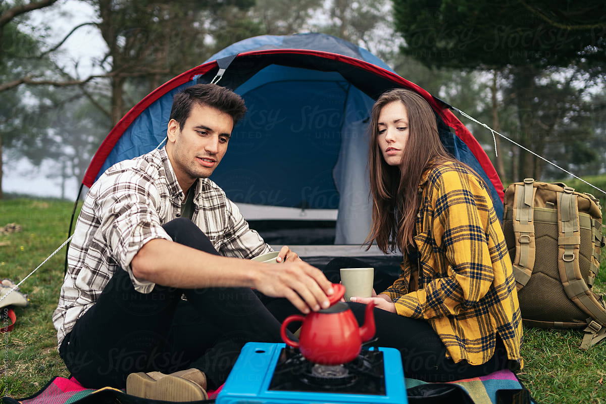Affectionate couple camping in the forest and using camping gas