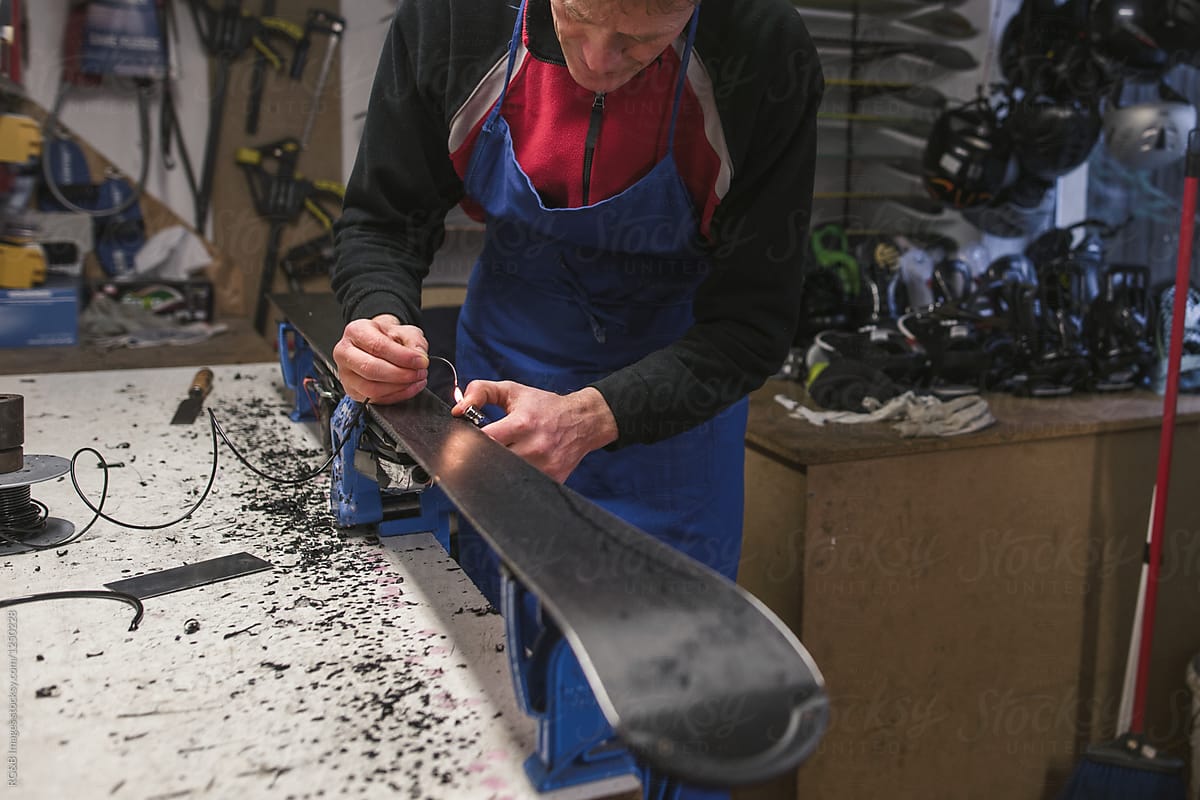 Mature man repairing skis in a workshop