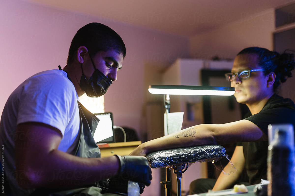 Artist tattoing a friend in his home tattoo studio