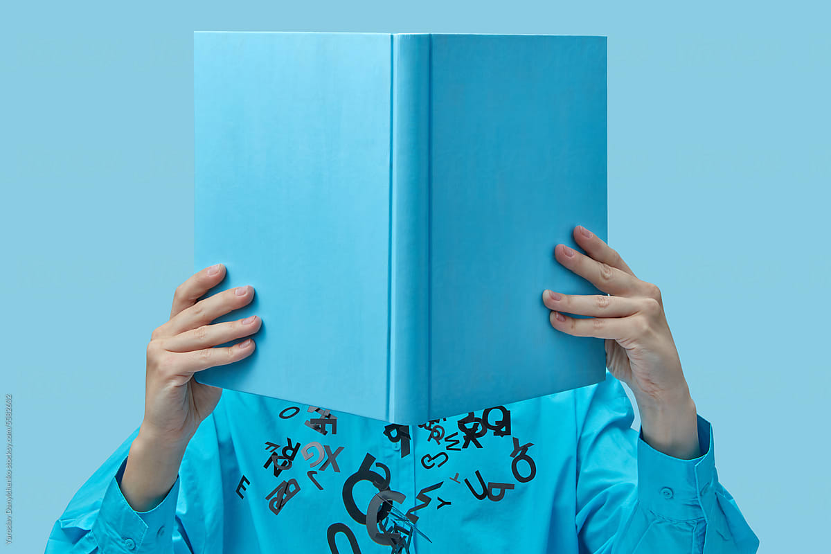 Girl holding book with black letters falling out.