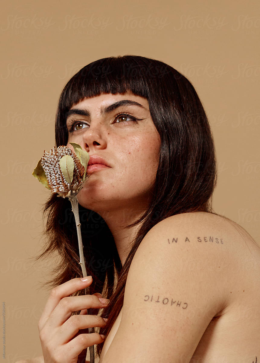 Woman with dreamy expression holding dead flower