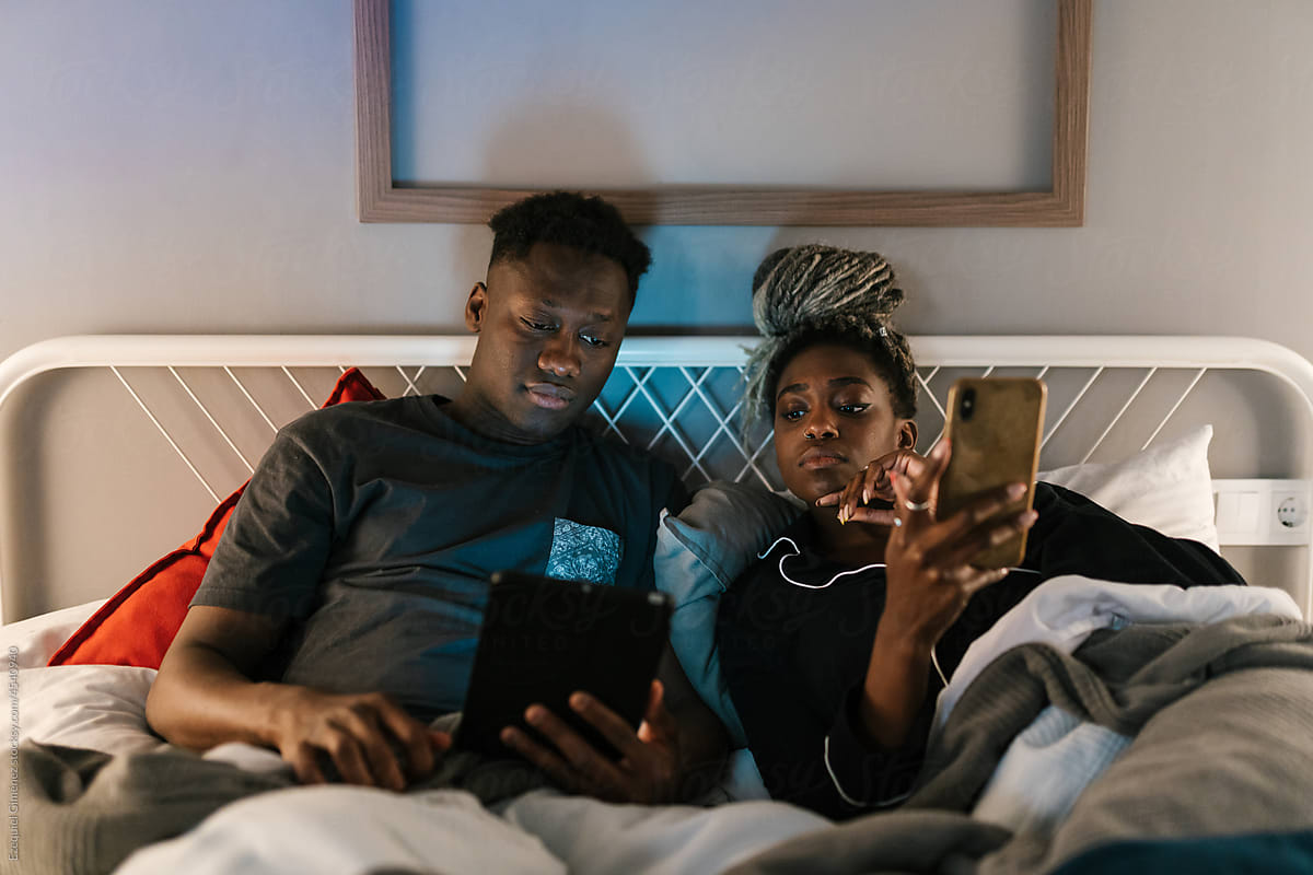 Couple using devices in bed