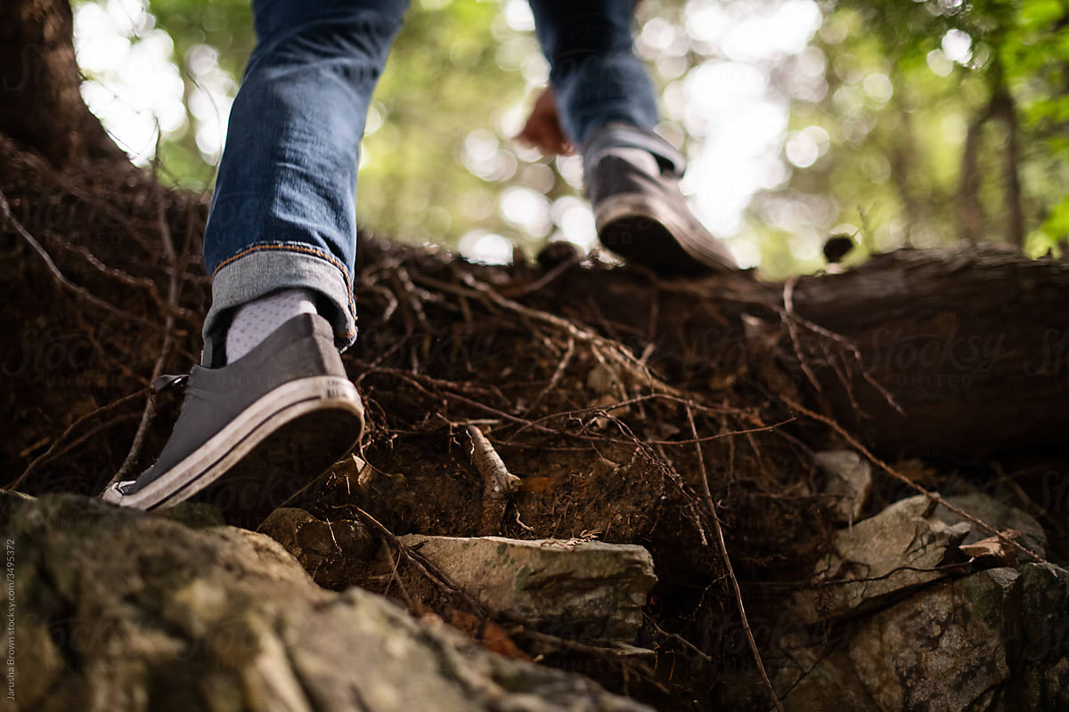 Close up of a man in sneakers hiking up a forest path