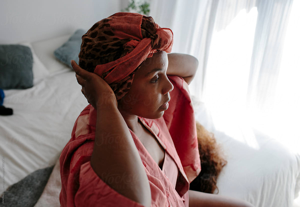 Woman adjusting head-wrap in bedroom