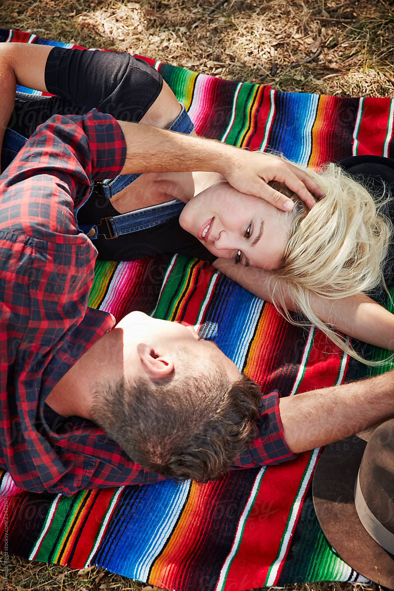 Millennial couple having a romantic moment lying on blanket in park