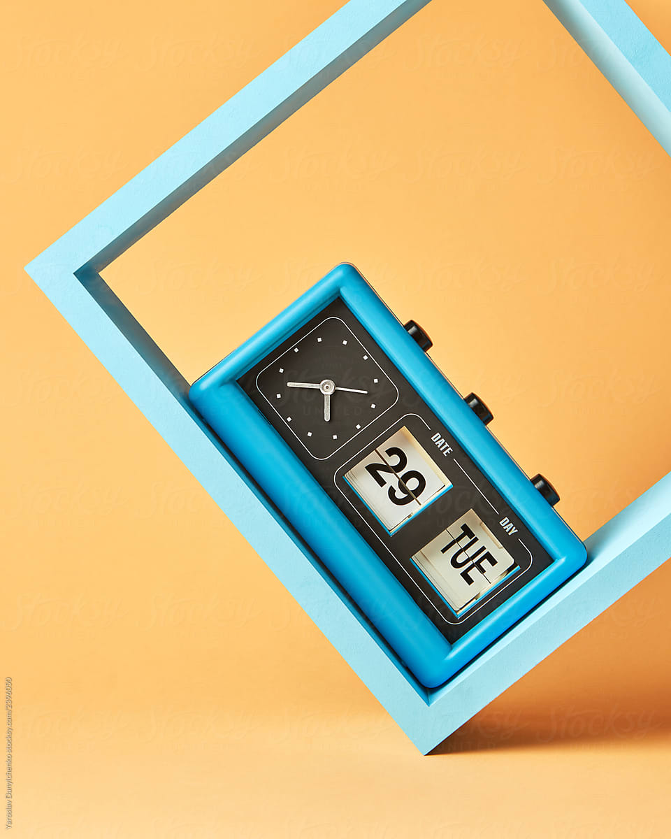 Retro flipping clock with calendar on wooden blue square shelf on an yellow background with copy space.