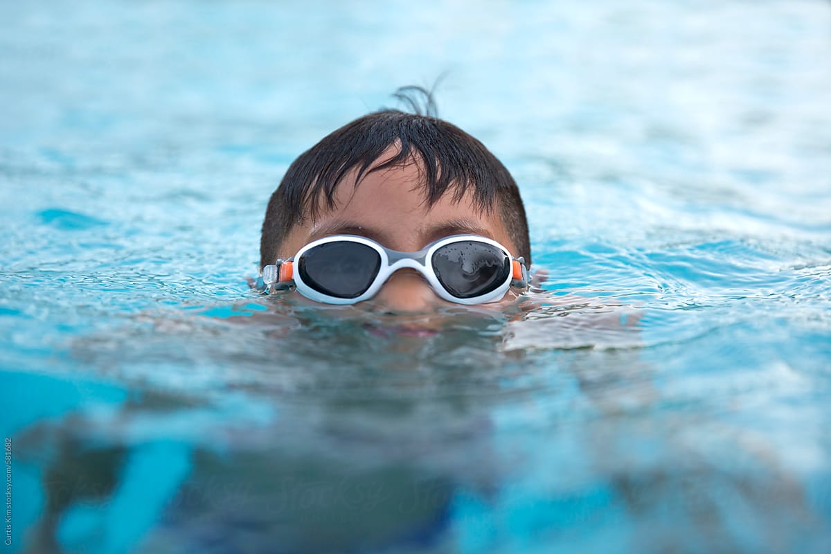 Young boy in pool wearing goggles