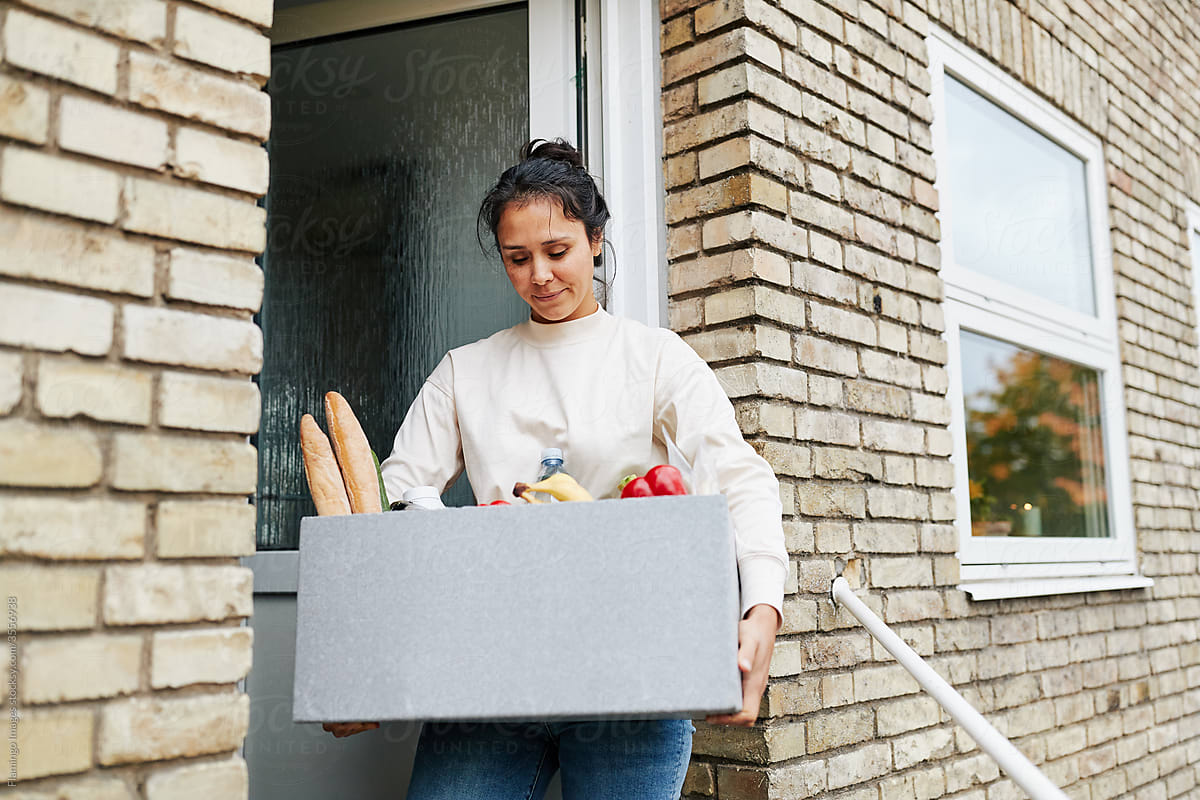 Smiling woman holding a grocery delivery box