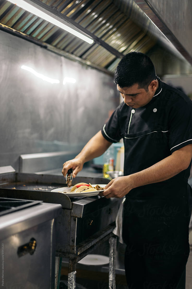 Latin chef plating tacos in professional kitchen