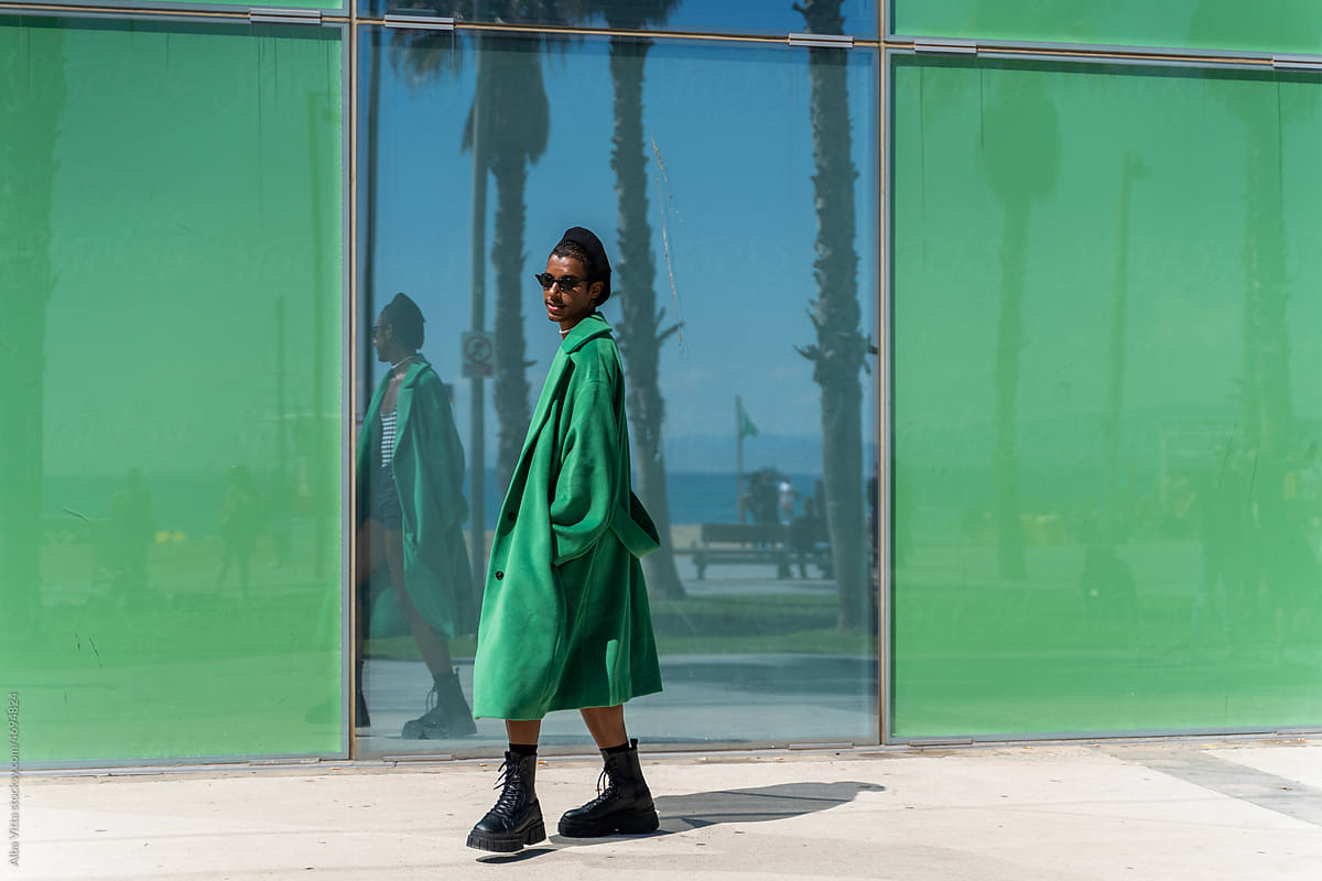 Black man in green outside building in coast town