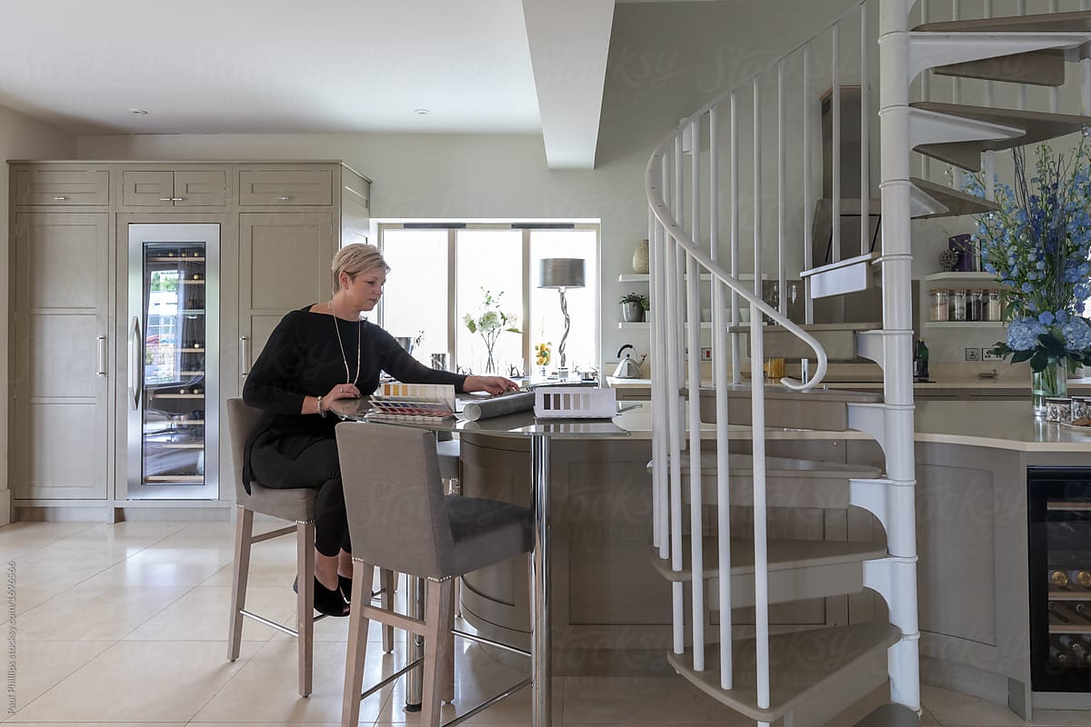 Interior designer planning changes to a kitchen whilst seated in the kitchen of a modern house.